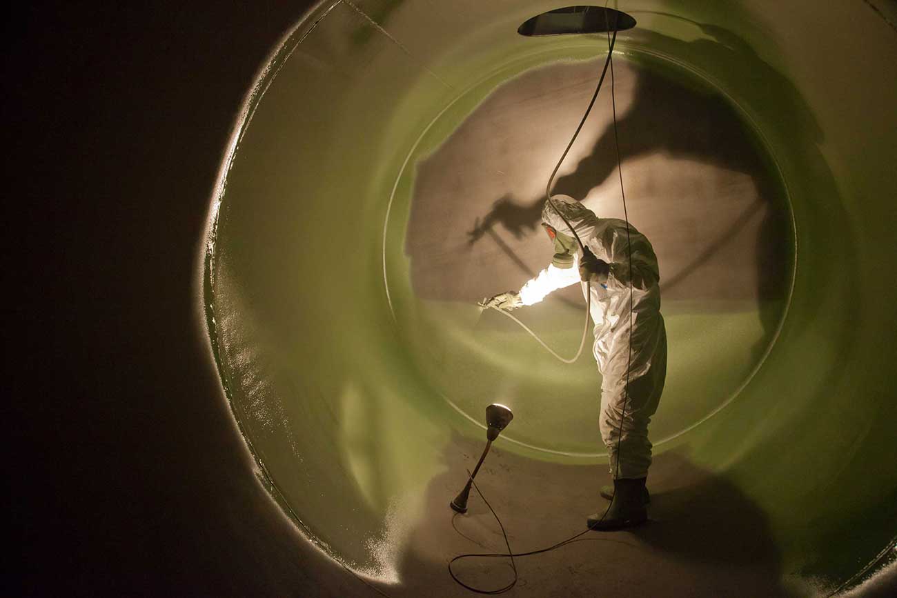 Mann der eine Kunststoffheißspritzbeschichtung im Inneren eines Tanks zum Tankschutz ausführt - Tankschutz Center Bayern GmbH